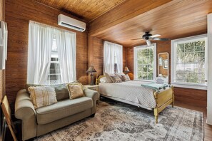 Una habitación con paneles de madera, una cama, un sofá y un ventilador de techo.