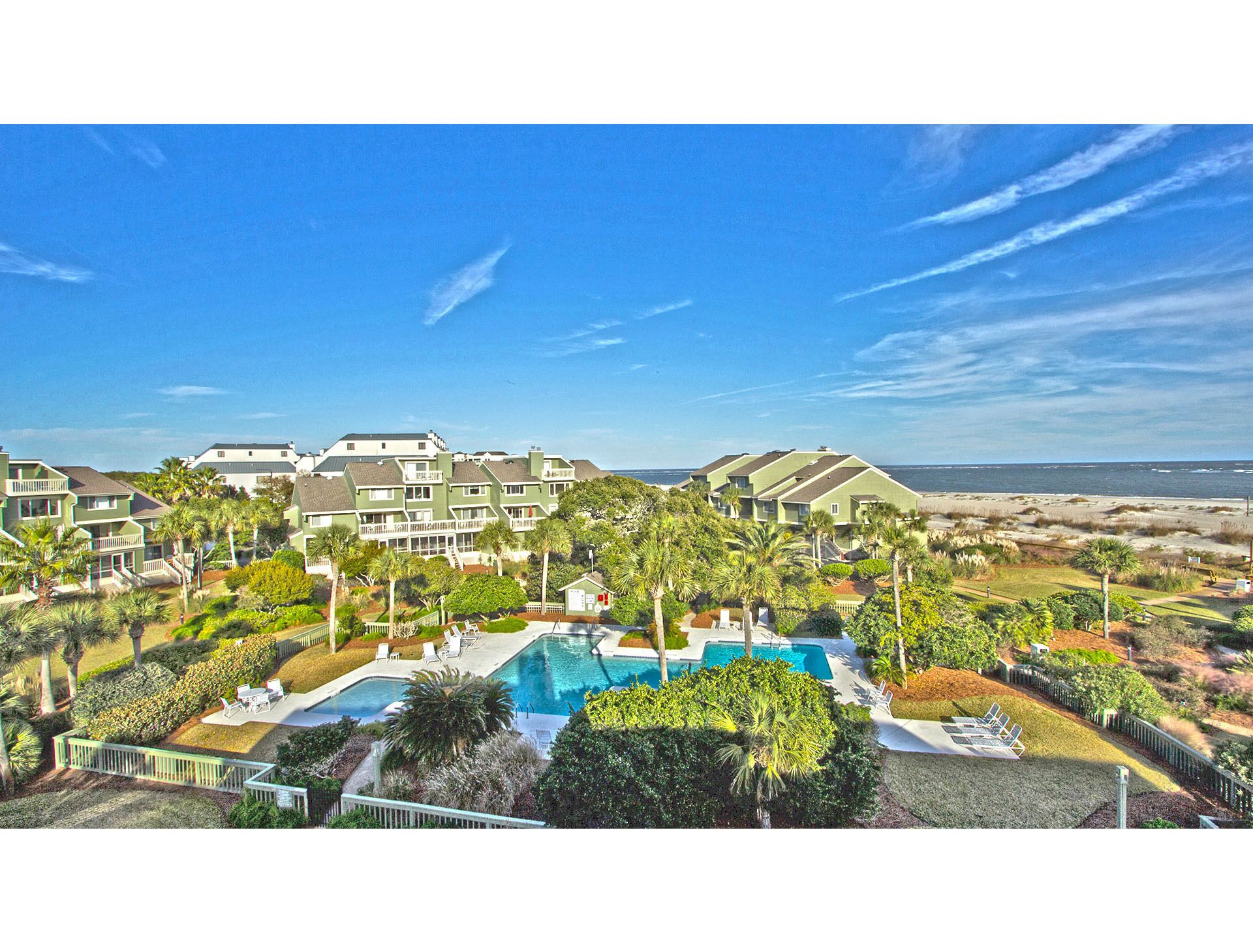 A resort with multiple-story buildings, a swimming pool, and a beach view.