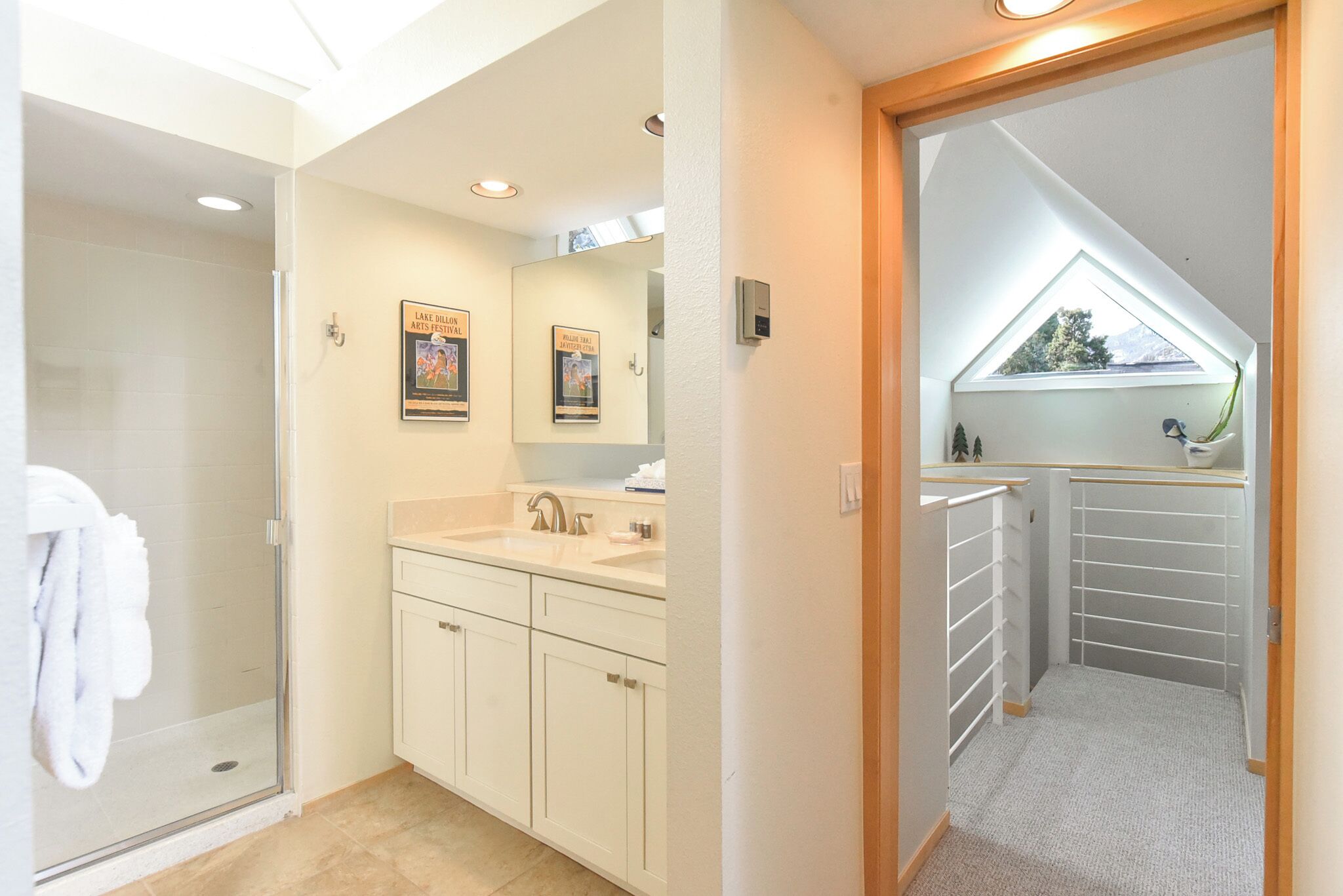 Un bagno moderno con cabina doccia in vetro, mobili bianchi, un lavabo e un lucernario.