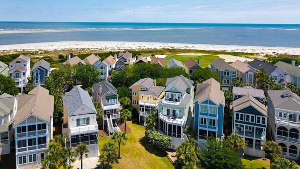 A coastal residential area with houses, a beach, and a clear sky.