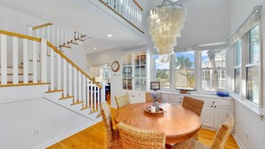 A spacious kitchen with a central island, white cabinetry, and a large window with a sailboat decoration.