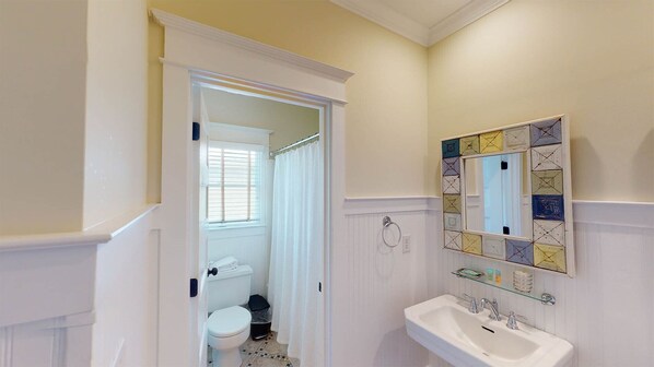 A bathroom with a white toilet, a sink with a mirror, and a shower area.