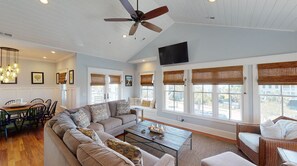 A spacious living room with a large sofa, a coffee table, and a dining area with chairs and a table.