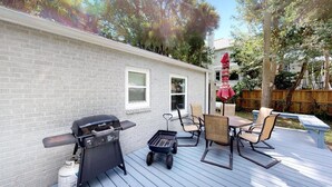 A backyard with a barbecue grill, a small table, and two chairs.