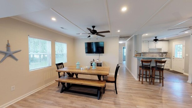 A spacious dining area with a wooden table, benches, and a ceiling fan.