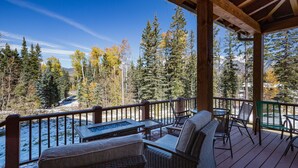 A covered deck with outdoor seating, a fire pit, and a view of a snowy landscape with trees. - Home Across from Purg - Views, Deck/Fire Pit/Ping Pong/Shuffleboard (Durango)