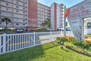 Et hotel kaldet "Sea Breeze of Madeira" med et hvidt hegn, parkeringsområde og et skilt med et sol- og bølgemotiv.