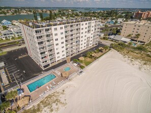 Et hotel med flere etager, en pool på taget og udsigt til stranden.