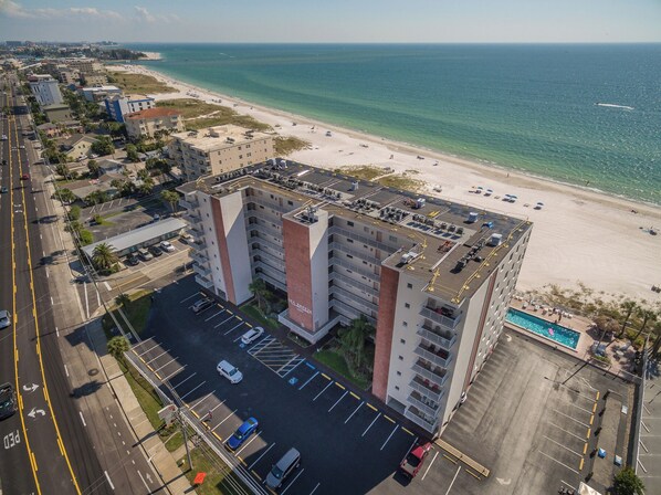 Un hotel de varios pisos con estacionamiento, vistas a la playa y una zona de piscina.