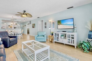 A spacious living room with a television, seating area, and a ceiling fan.