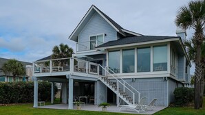 Une maison à deux étages dotée d’un patio couvert, d’un escalier et d’un espace piscine.