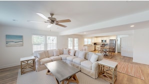 A spacious living room with a large L-shaped sectional sofa, a wooden coffee table, and a ceiling fan. - 4 bedrooms, walk to the beach, large screened in porches! (Isle of Palms)