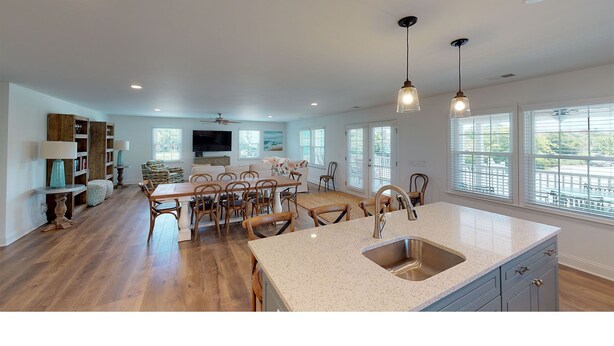 A spacious kitchen with a large island, wooden flooring, and a view of the outdoors through large windows. - 4 bedrooms, walk to the beach, large screened in porches! (Isle of Palms)