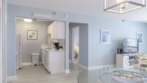 A modern kitchen with white cabinets, a built-in oven, and a small island with a sink.