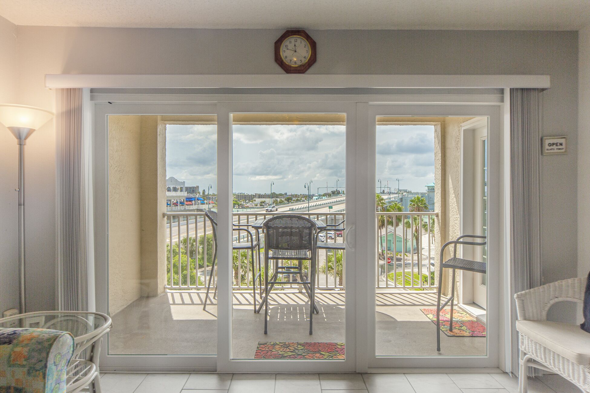 Ein Zimmer mit einer Schiebetür zu einem Balkon im Freien, mit Stuhl und Tisch.