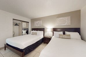 Ett hotellrum med två sängar, en garderob och konstverk på väggarna.