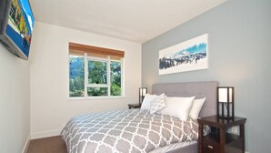 A bedroom with a bed, two bedside tables, a window, and a wall-mounted picture. - Eagle Lodge 432 MOUNTAIN VIEWS + VILLAGE LOCATION! Professionally Managed + Cleaned (Whistler)