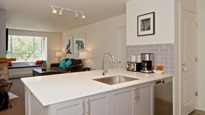 A modern kitchen with a central island, white cabinetry, and a built-in dishwasher. - Eagle Lodge 432 MOUNTAIN VIEWS + VILLAGE LOCATION! Professionally Managed + Cleaned (Whistler)