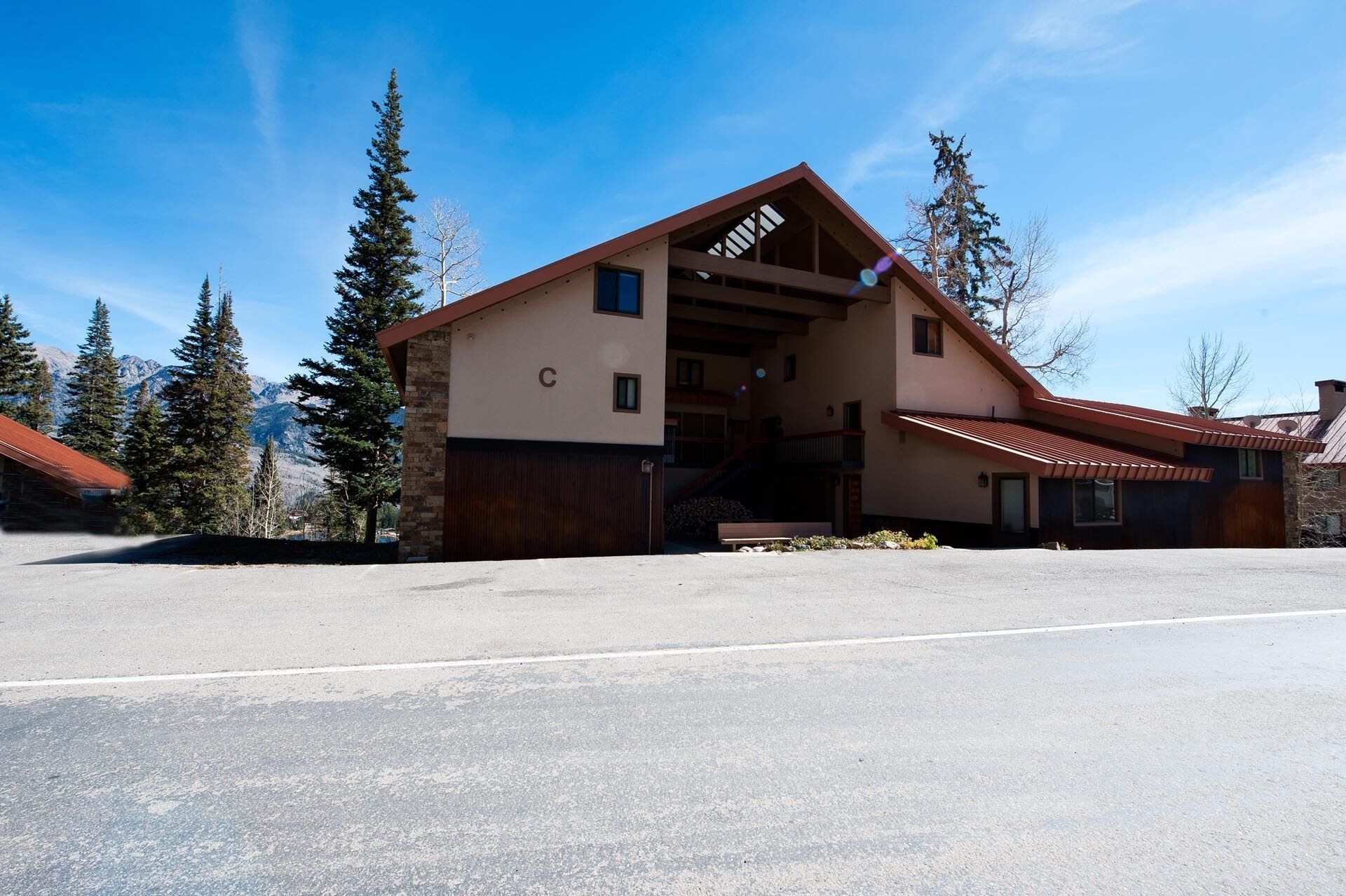 A lodge with a large wooden entrance, a ski lift visible in the background, and a mountain view.
