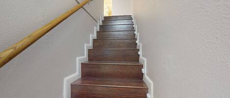 A wooden staircase with white trim against a plain wall.