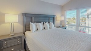 A bedroom with a large bed, two bedside tables, and a window with blinds. - 2-Level Madeira Beach Condo, Pool, Marina, Walk to Beach, Shops,  Dining +Tickets to Top Activities! (Madeira Beach)