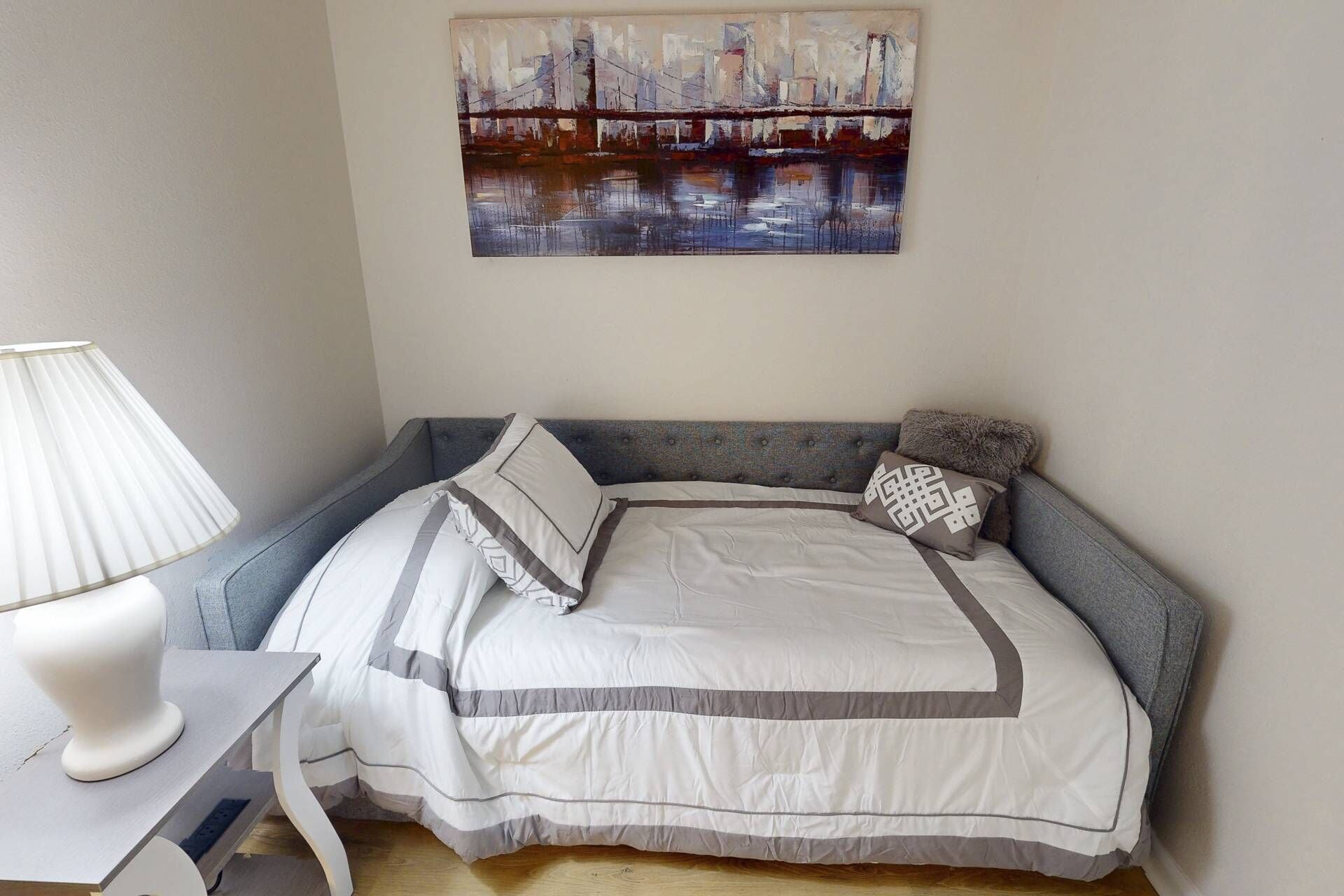 Une chambre à coucher avec un lit, une lampe et un tableau au mur.