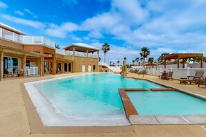 Ein Swimmingpool mit weißem Rand, Liegestühlen und einer überdachten Sitzgelegenheit.