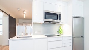 A modern kitchen with white cabinetry, a stainless steel refrigerator, and a microwave. - Chic, Modern | Walk Anywhere @ Viking Lodge 206 (Telluride)