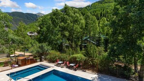 A swimming pool with two separate sections, surrounded by a wooden fence and trees.