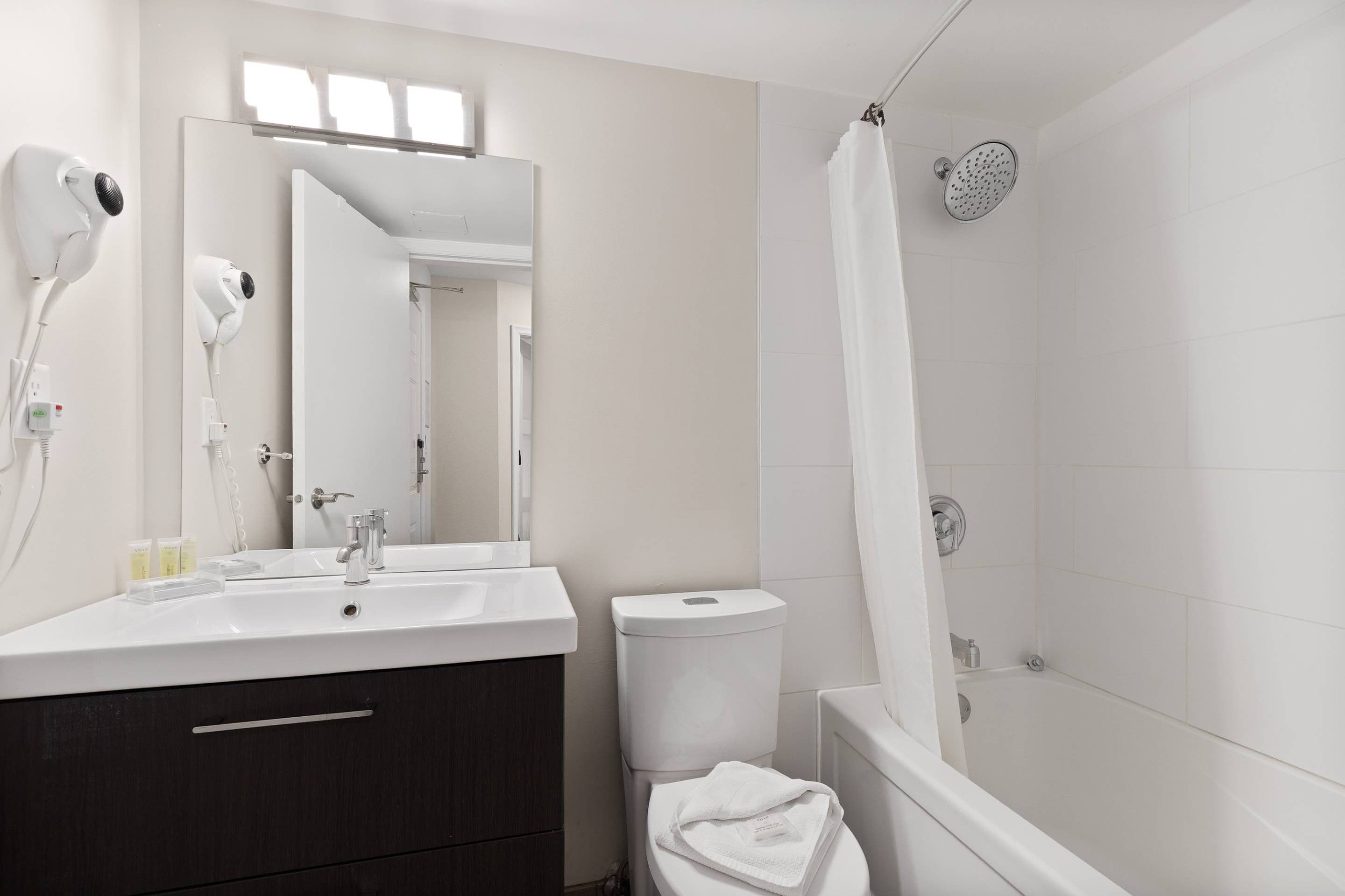 A modern bathroom with a white sink, mirror, and shower.