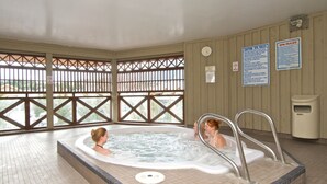 A hot tub area with two people, a clock, and spa rules signs on the wall. - Renovated, Village location. Walk to lifts ,amenities, modern décor, hot tub closed for renovation. (Whistler)