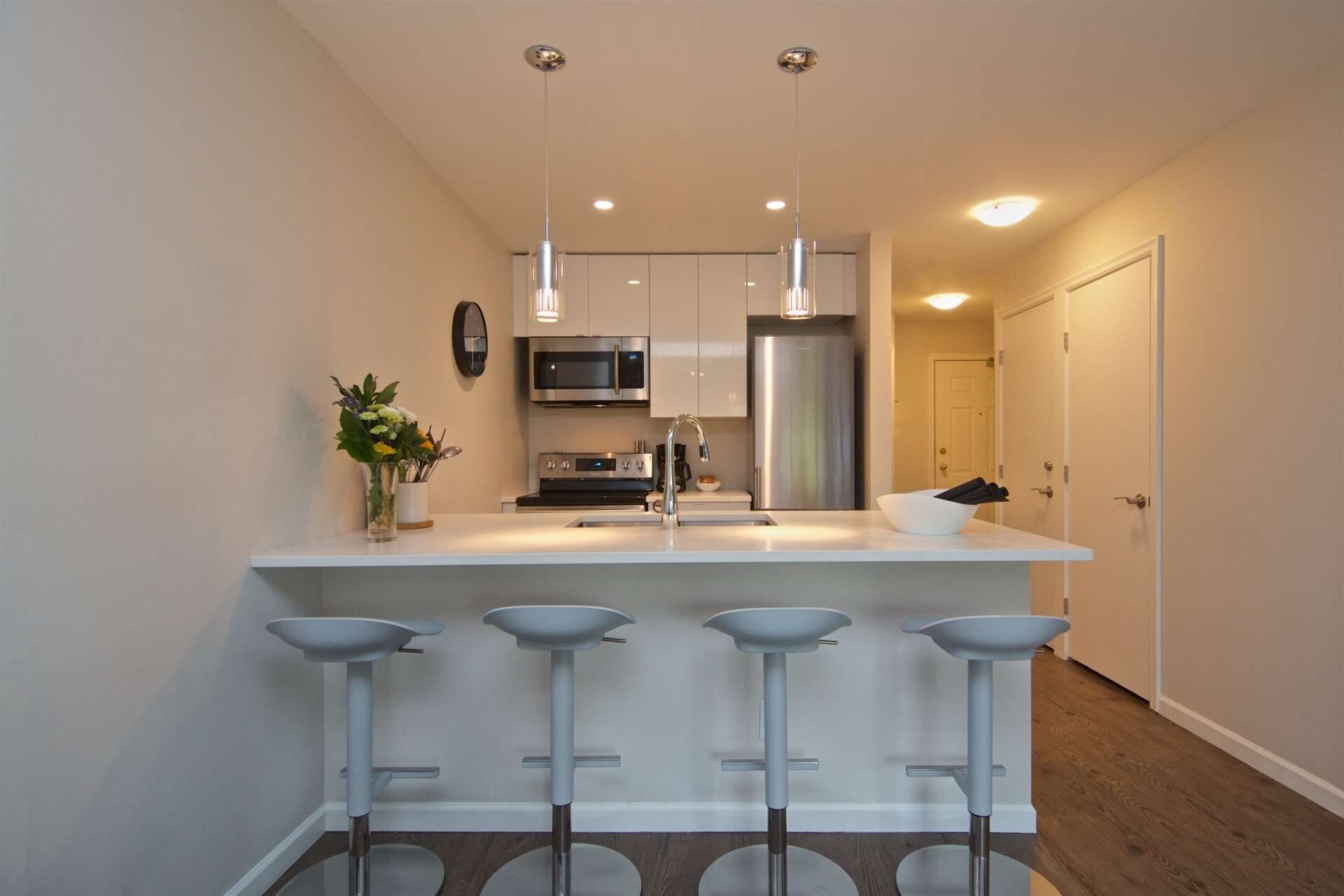 A modern kitchen with a central island, stainless steel appliances, and a bar area with stools.