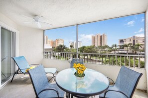 Ein Balkon mit Glastisch, zwei Stühlen und Deckenventilator.