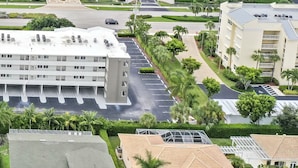A high-rise hotel with multiple floors, a tennis court, and a parking area.
