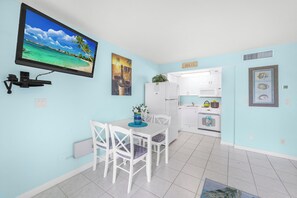 A compact kitchen with white cabinets, a microwave, and a refrigerator.