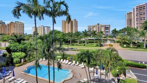 A resort with a swimming pool, palm trees, and high-rise buildings in the background.