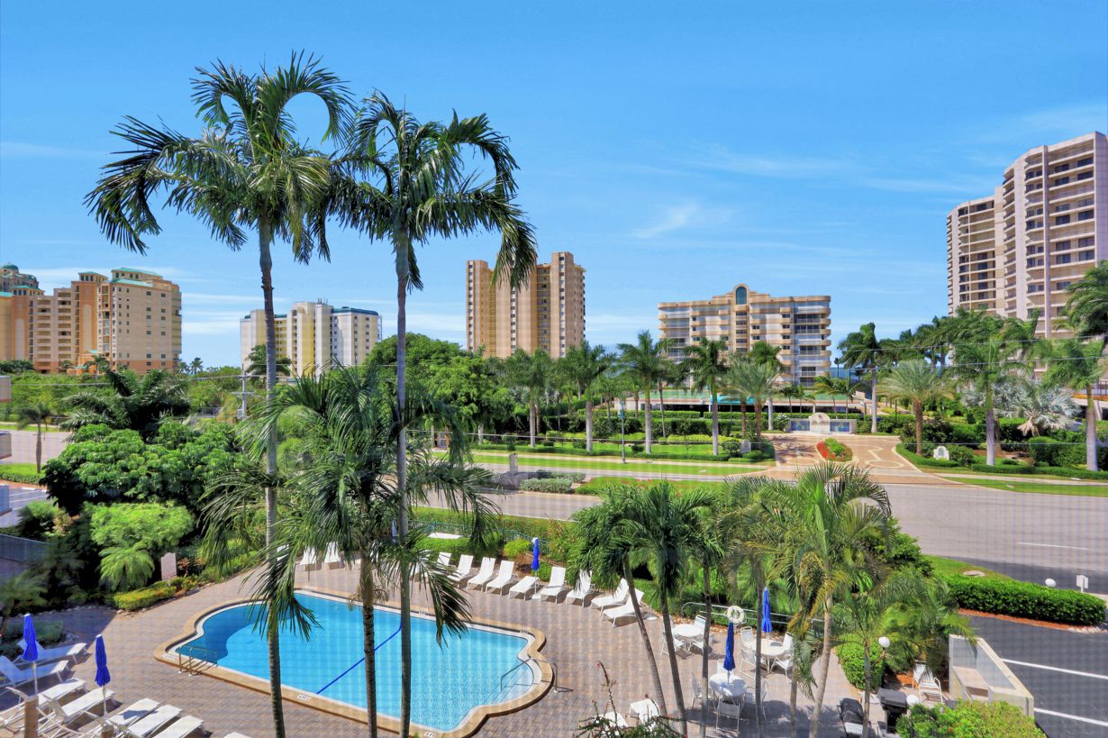 A resort with a swimming pool, palm trees, and high-rise buildings in the background.