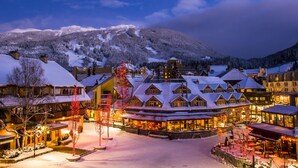 A snow-covered lodge with a central courtyard, surrounded by buildings and a mountain backdrop. - Charming Creekside Townhouse. Easy WALK to the Gondola. Professionally Managed + Cleaned (Whistler)