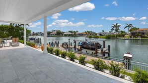 Un espacio al aire libre techado con vistas a un lago, barcos amarrados y un puerto deportivo.