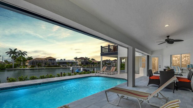 Un área de piscina moderna con vista a un puerto deportivo y casas.