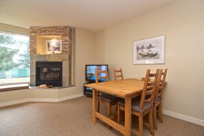 A dining area with a fireplace, a television, and framed artwork on the wall.
