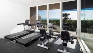 A fitness area with treadmills and a stationary bike, overlooking a scenic view. - Beachfront Condo | Huge Views/Pools/Tennis/Grills (Marco Island)
