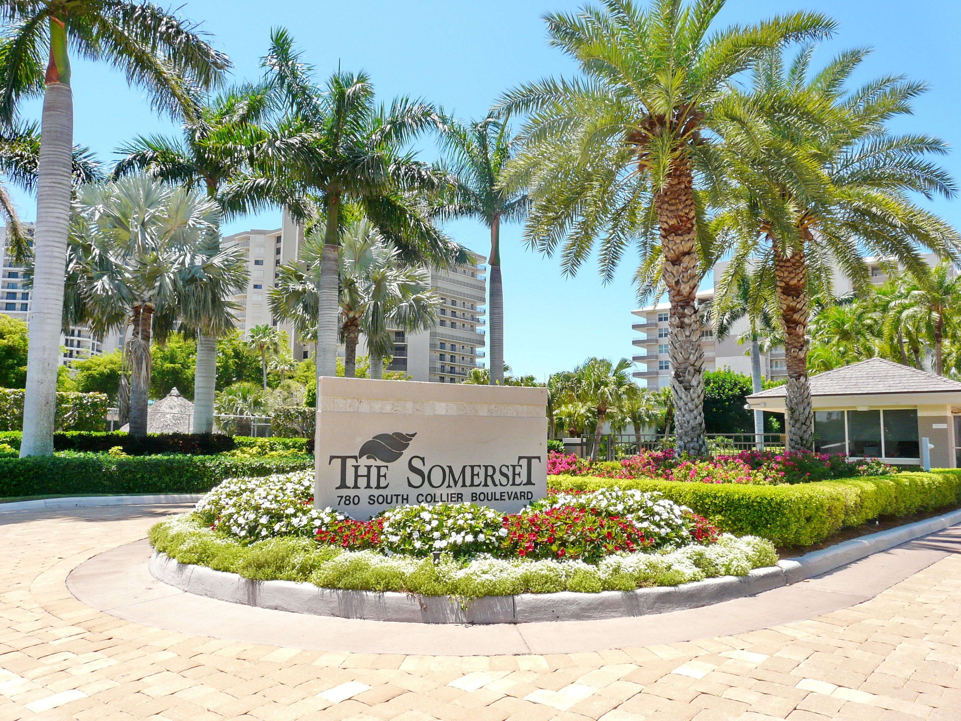 Naamplaatje voor The Somerset aan 780 South Collier Boulevard, omringd door aangelegde tuinen en palmbomen.