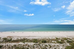 A beach with a clear sky, calm sea, and sparse vegetation. - Beachfront Condo | Huge Views/Pools/Tennis/Grills (Marco Island)