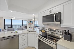 A modern kitchen with a built-in oven, microwave, and a large island with a sink. - Inviting Beachfront Condo | Pool, Spa & Views (Marco Island)