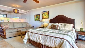 Ein Schlafzimmer mit einem großen Bett, einer Couch, einem Esstisch und einer Küchenzeile im Hintergrund.
