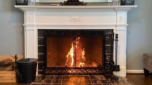 A fireplace with a fire, a black trash bin, and a decorative mantelpiece. - Southern-Style Home w/ Luxe Kitchen: 15 Min to DC! (Arlington)