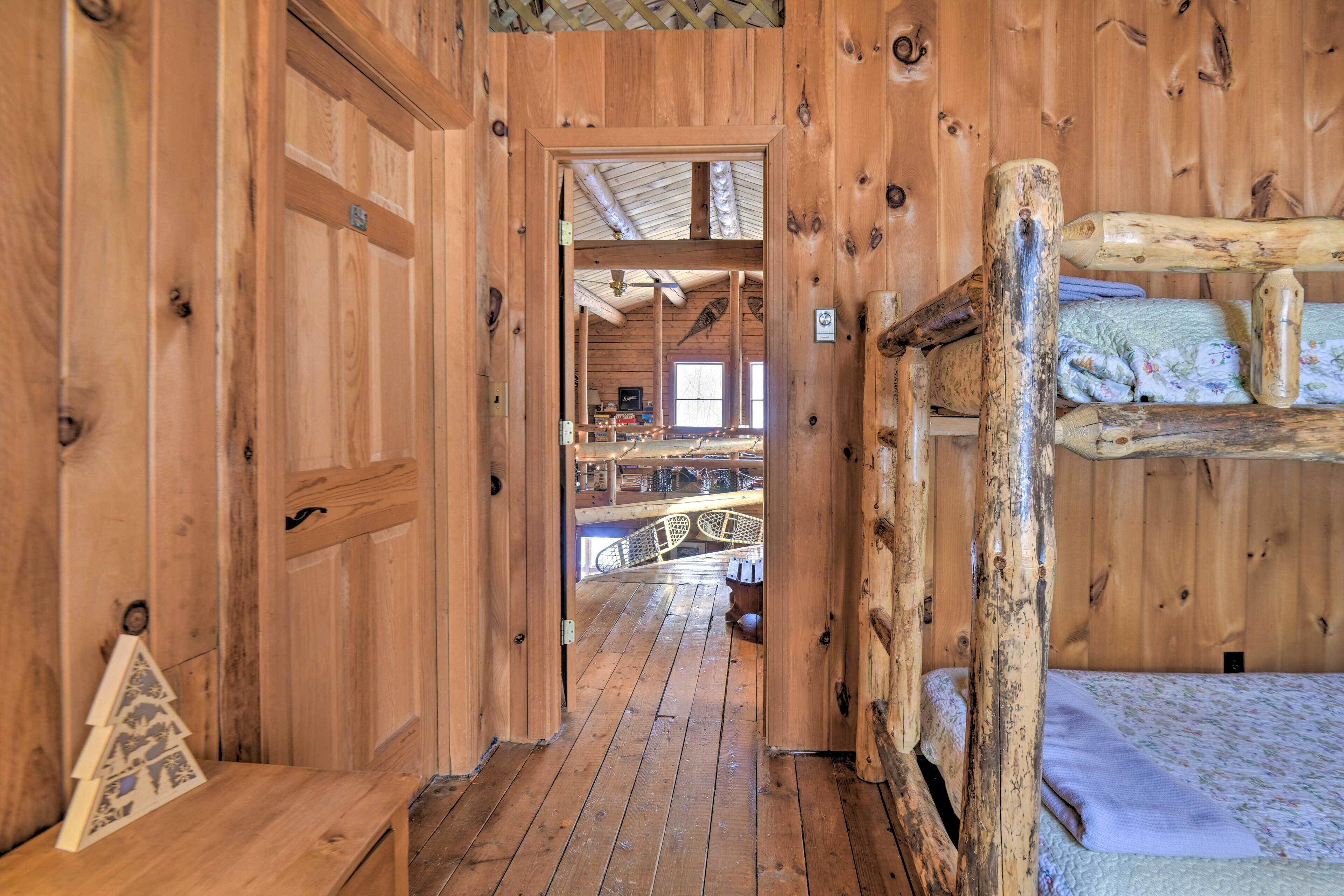 A wooden cabin interior with a bunk bed, a wooden bench, and a small Christmas tree.