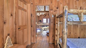 A wooden cabin interior with a bunk bed, a wooden bench, and a small Christmas tree.