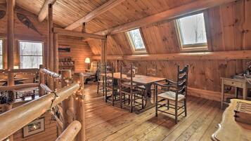 A cozy wooden cabin with a dining area, a loft bedroom with skylights, and a rustic decor.